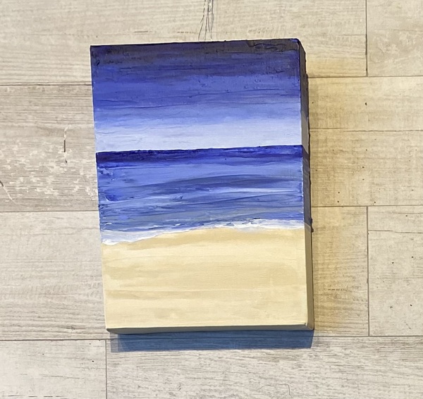 rectangular painting of beach Light tan sand on bottom third of piece meeting the blue ocean with the top third of the painting different shades of light blue to midnight blue of the sky