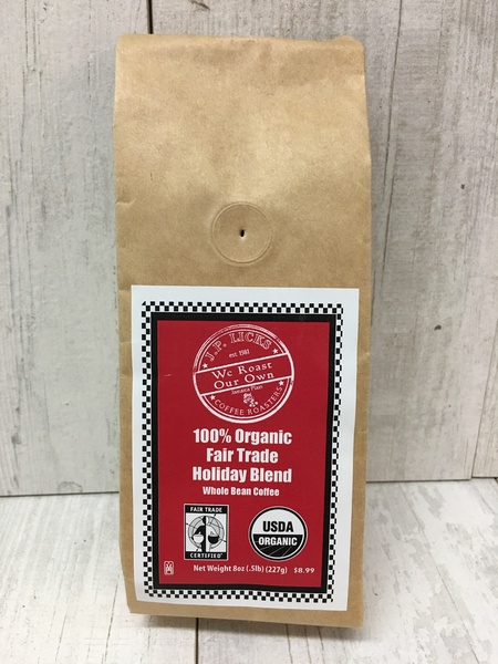 Brown paper coffee bag with red label reading 100 organic fair trade holiday blend Whole Bean Coffee Net Weight 8 oz with JP Licks coffee logo On white planking background 