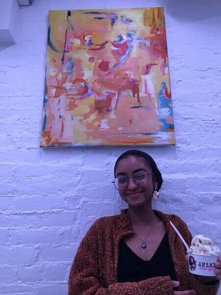 young woman holding ice cream in front of abstract painting of pink orange blue yellow colors 