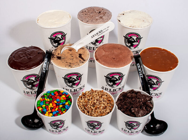 Three rows of white JP Licks quart containers Three in back row filled with ice cream four in middle row - one filled with hot fudge other three with ice cream second one in from left with white scoop inside front row is three containers of topping