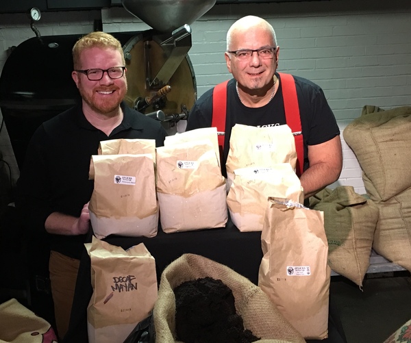 City Councilor Matt OMalley and JP Licks FounderOwner Vincent Petryk in front of coffee roaster and behind bags of coffee grounds for composting 