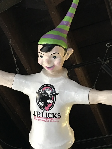 Ceramic Elf wearing purple and green striped hat and JP Licks tshirt flying from ceiling