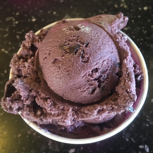 Black Raspberry Chip Hard Yogurt as seen from above in cup on black speckled service Yogurt is dark pink 